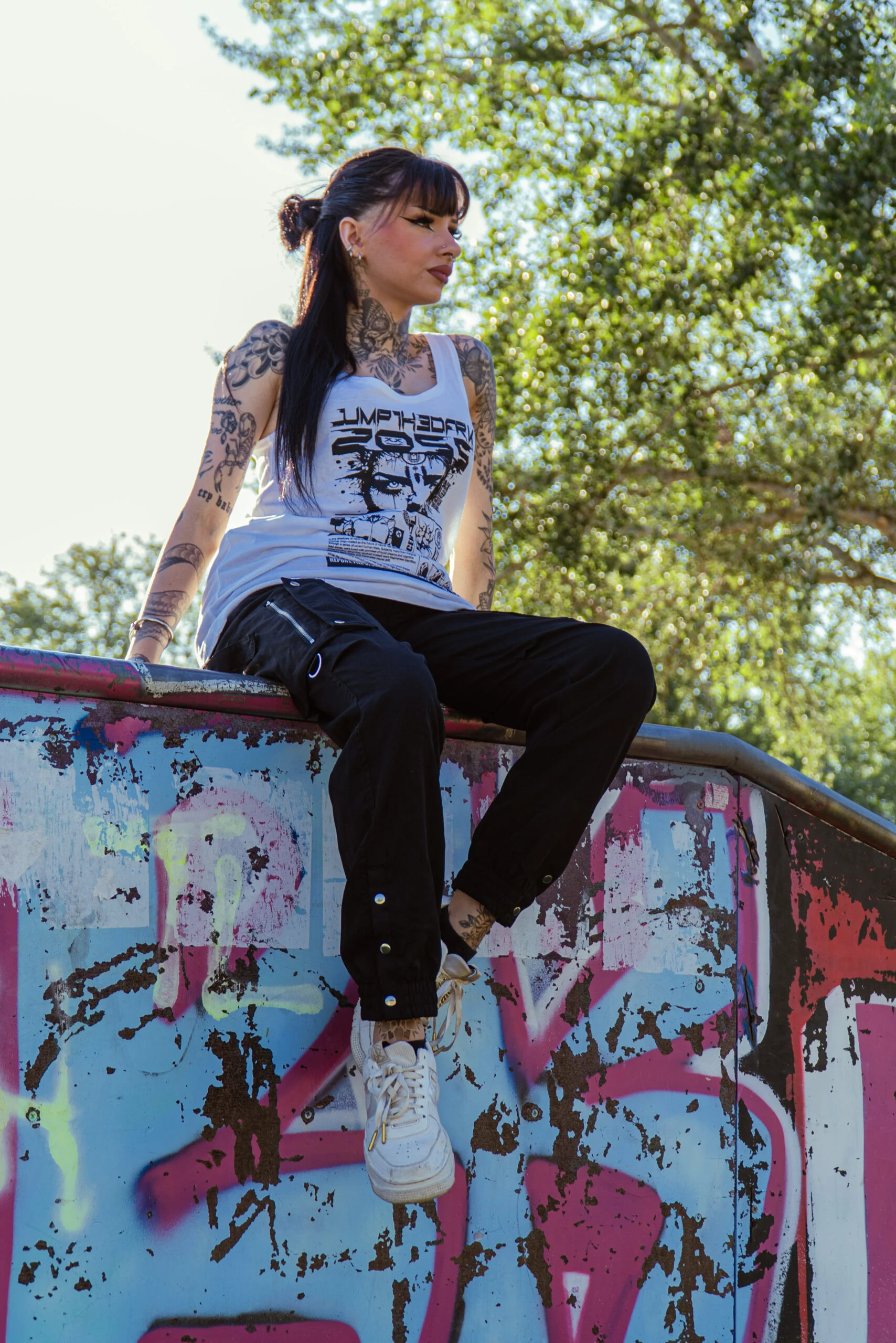 Portrait d’une femme assise sur une rampe de skate couverte de graffitis