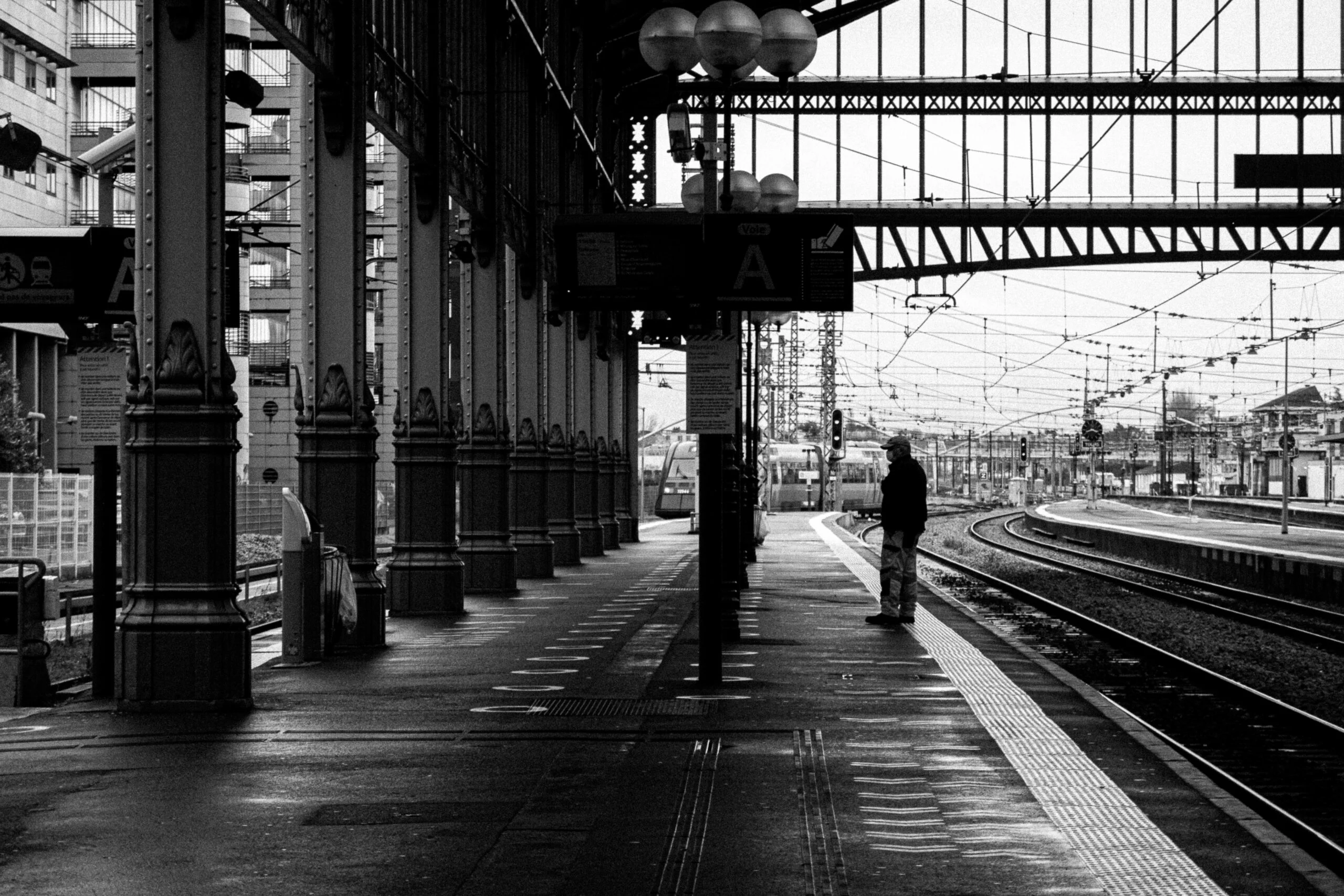 Voyageur seul sur le quai d’une gare en noir et blanc