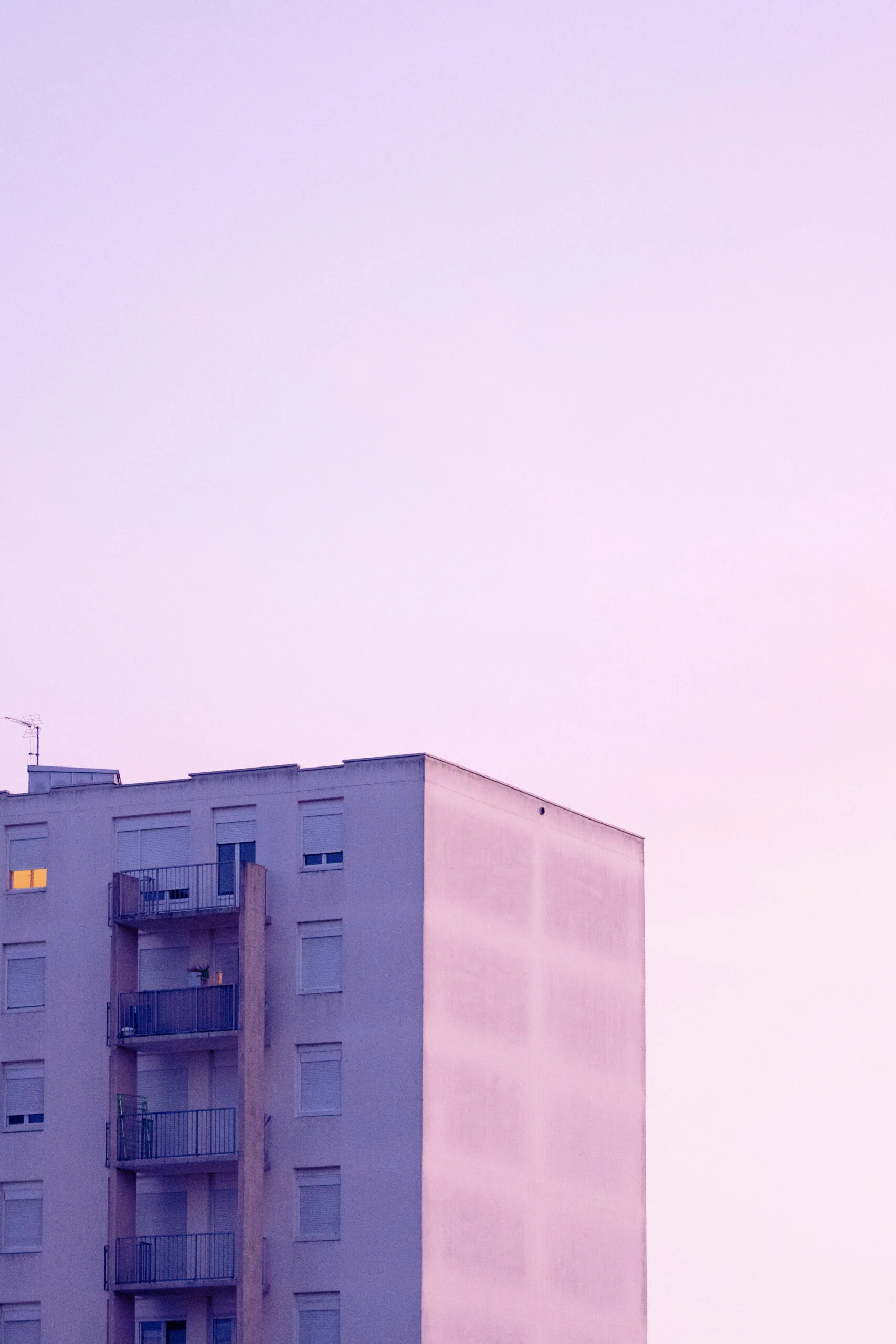 Façade d’immeuble teintée de rose au crépuscule