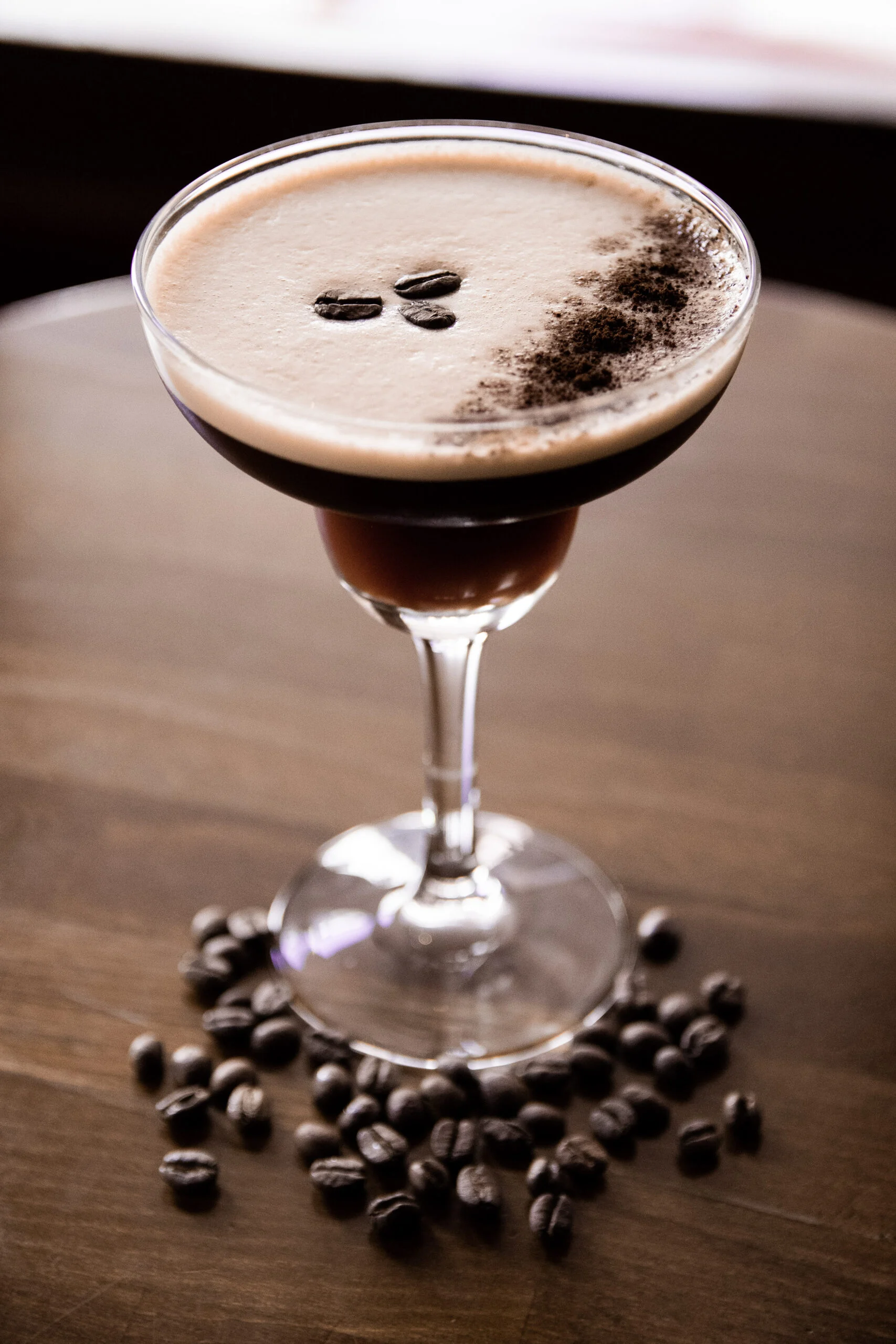 Cocktail au café servi dans un verre à pied et entouré de grains