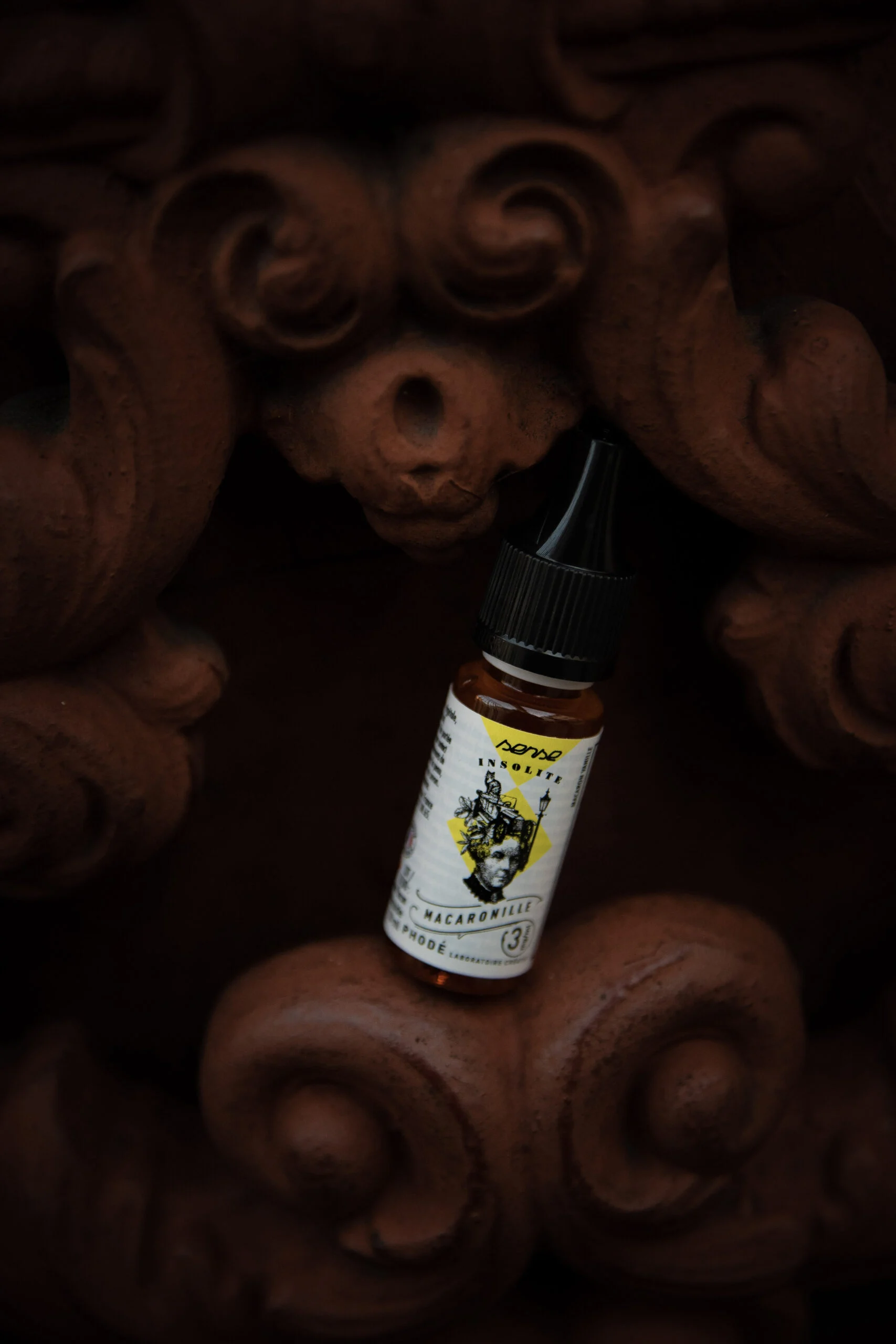 Flacon de e-liquide mis en scène sur du bois sculpté