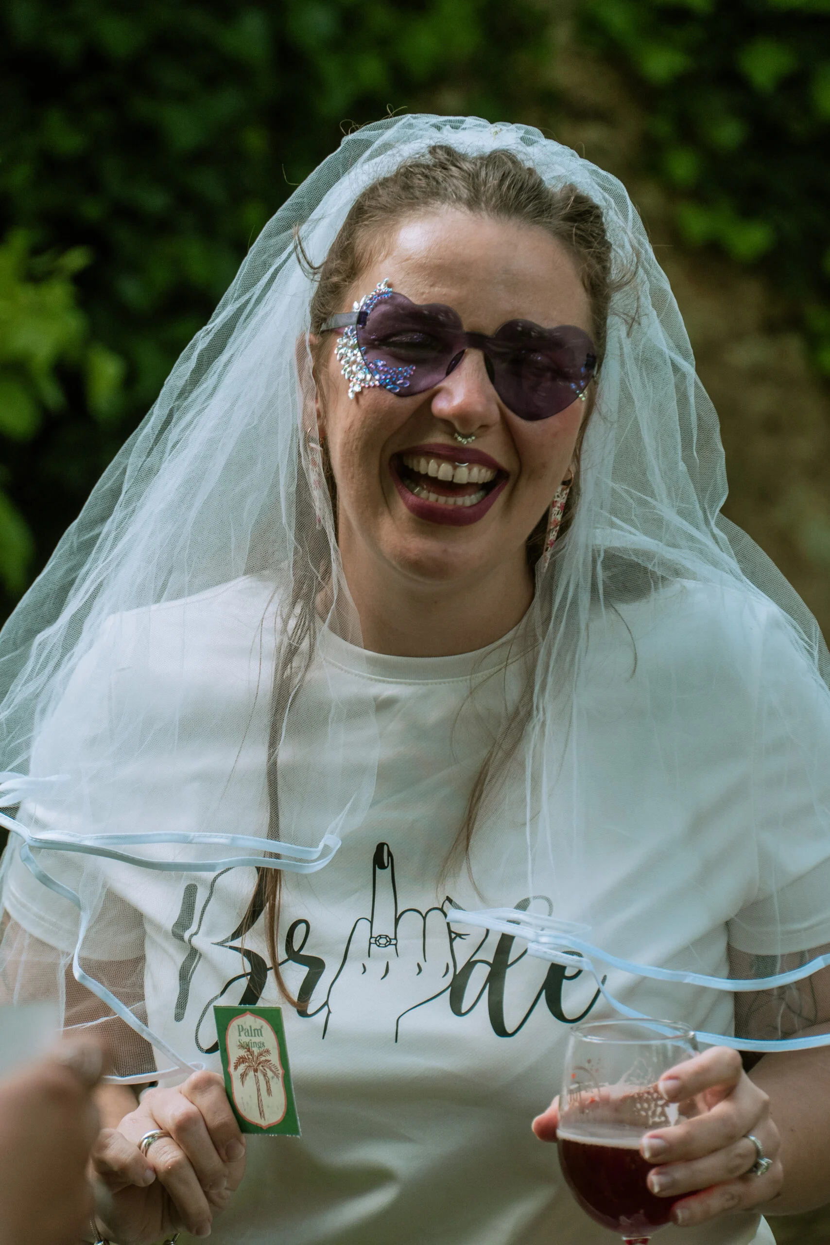 Future mariée riant avec un voile et des lunettes de soleil